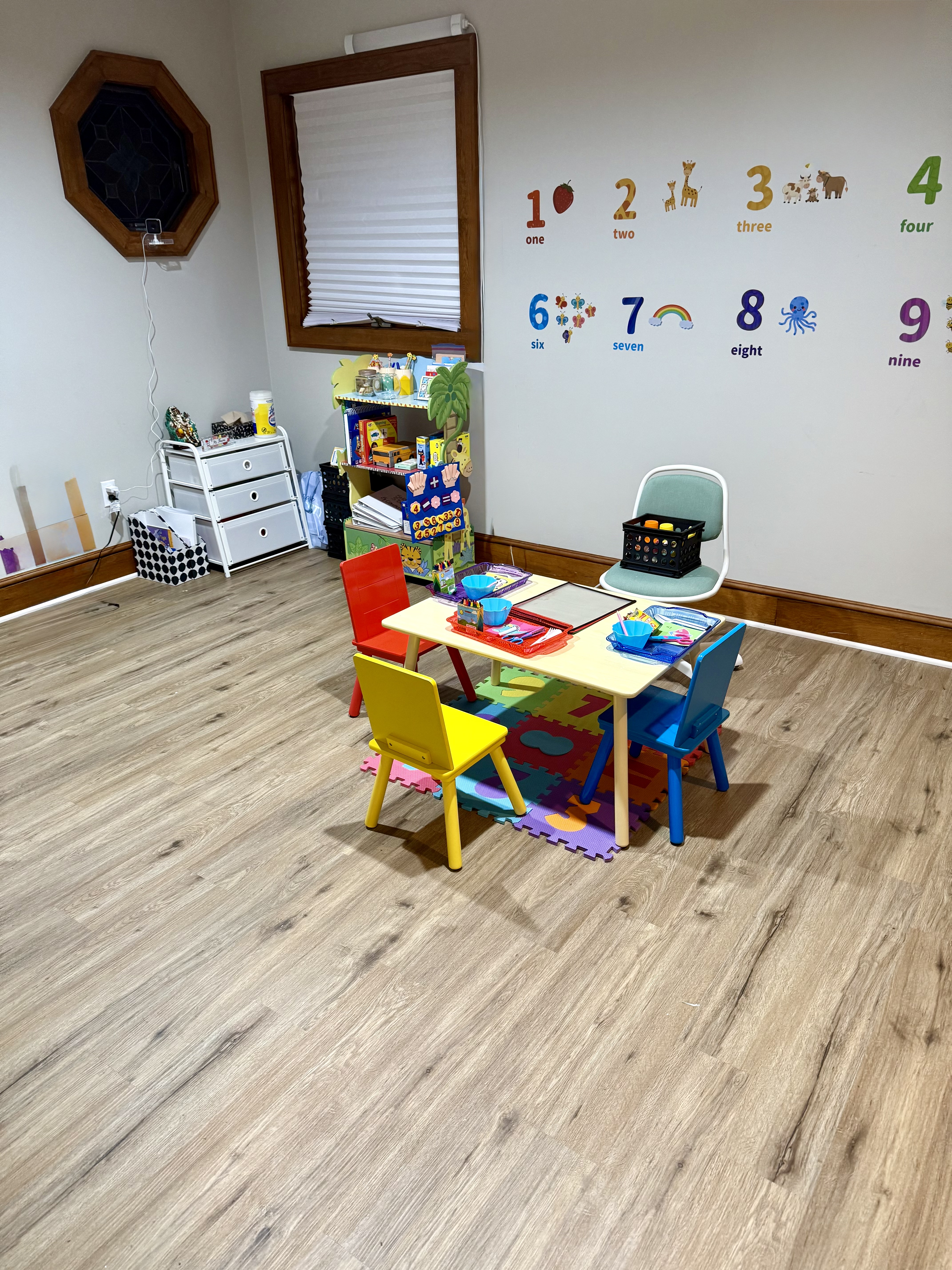 ThinkAutWise's bright, organized learning room with a kids' activity table, number wall decals, and learning materials